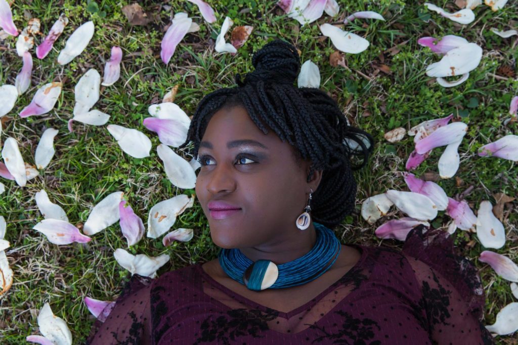 Sofi Seck formerly of Sofi Seck Photography lays in the grass among the magnolia tree leaves gazing to her right 