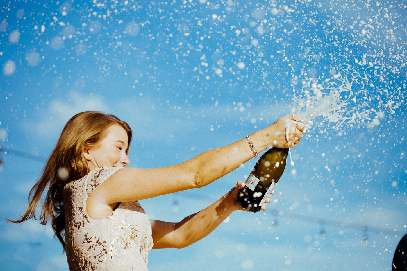 Bridesmaid pops a bottle of champagne as she enters the roof top reception - the beverage sprays happily everywhere
