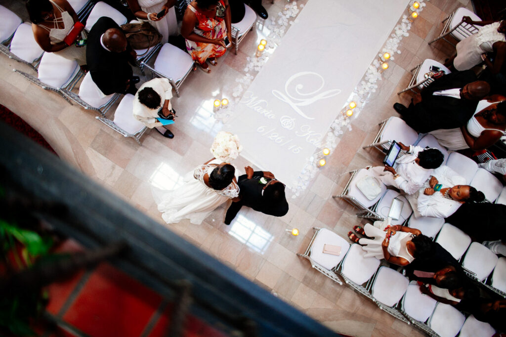 A bride and her father begin the walk down the aisle with flower petals and candles along the chairs, and a monogram with their name and wedding date on the runner. They are in the Barnett on Washington getting married in St.Louis MO