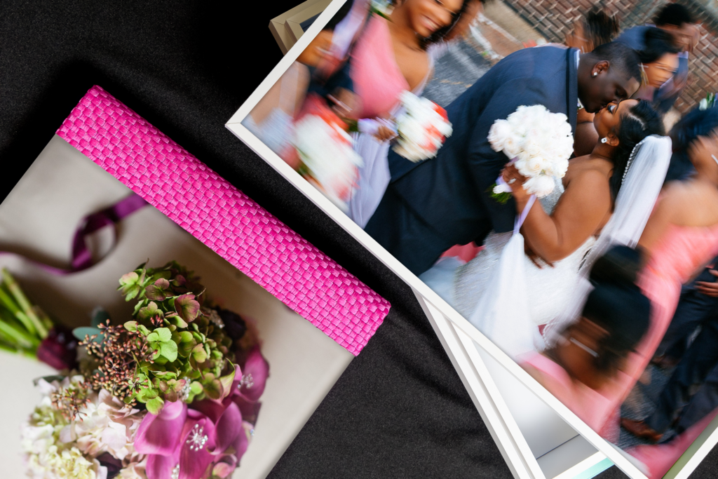 Two St Louis wedding albums partially showing one has an image of a couple while their bridal party is blurred and the other has a pink woven spine with a bouquet on the cover