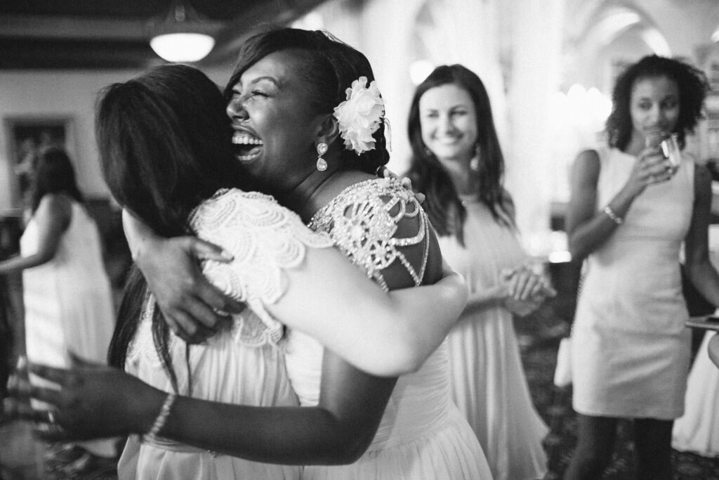 Bride laughing and squeezing her guest in a hug during a St. Louis wedding ceremony, candid wedding photography